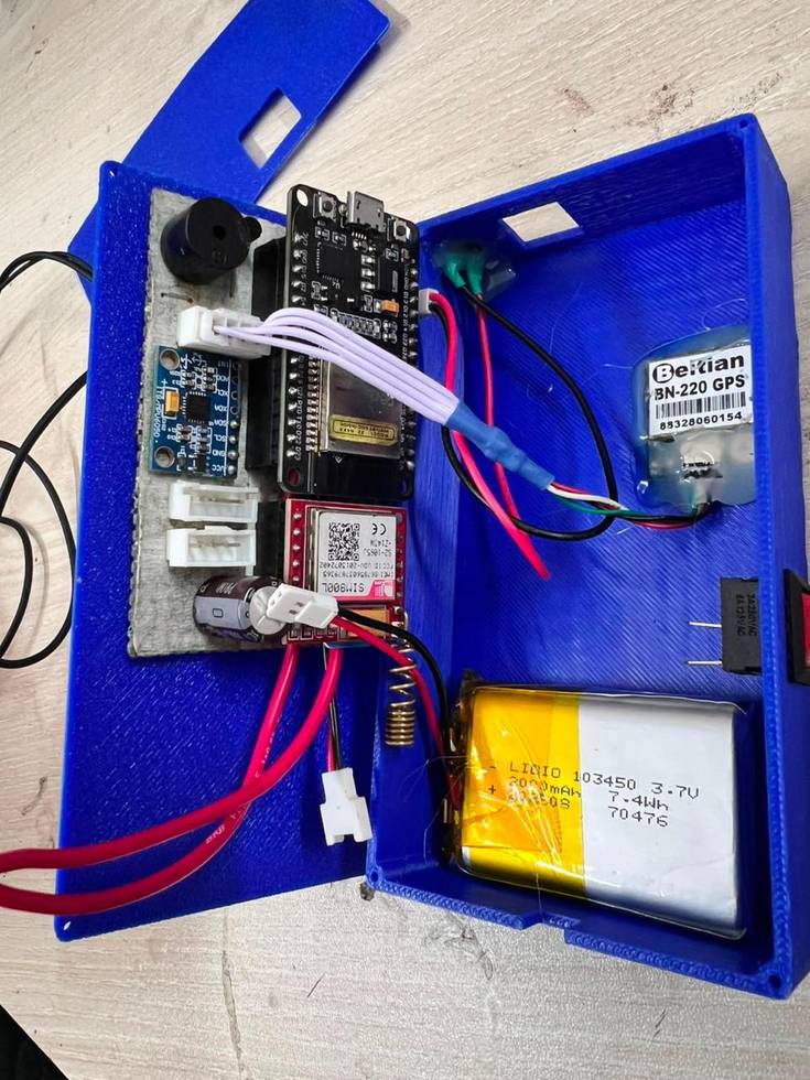 The opened enclosure showing the ESP32, the Beitian BN-220 GPS module, the SIM800L GSM module, the LiPo battery cell, and the red power switch.